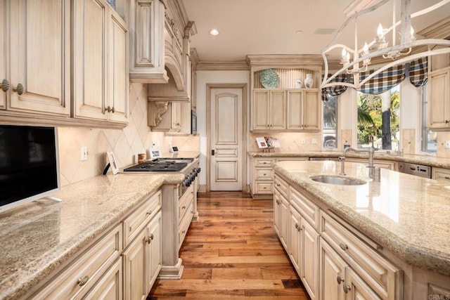 kitchen featuring decorative light fixtures, sink, light stone counters, crown molding, and light hardwood / wood-style flooring