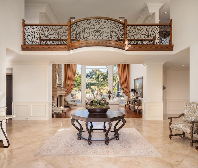 entrance foyer featuring a towering ceiling, ornamental molding, and ornate columns