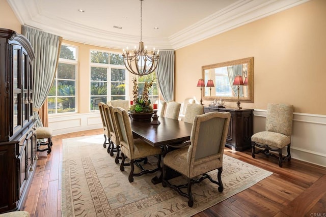 dining room with hardwood / wood-style floors, crown molding, and a chandelier