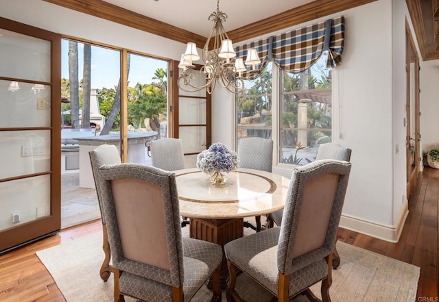 dining space featuring ornamental molding, a healthy amount of sunlight, a chandelier, and light hardwood / wood-style floors