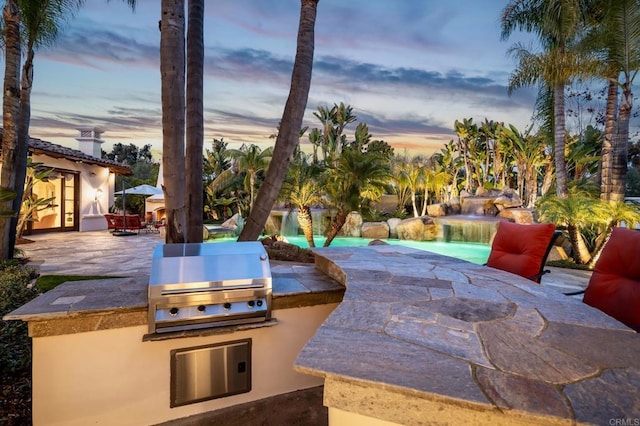 patio terrace at dusk featuring area for grilling