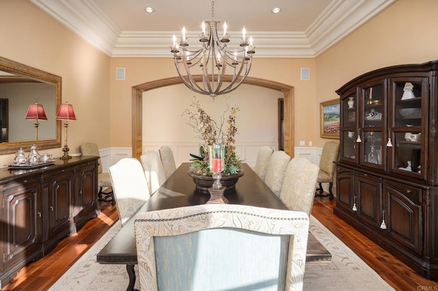 dining area featuring dark wood-type flooring, ornamental molding, and a notable chandelier