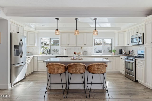 kitchen featuring a breakfast bar, light hardwood / wood-style flooring, appliances with stainless steel finishes, a kitchen island, and white cabinets