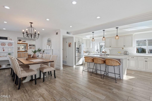 dining room featuring crown molding, sink, light hardwood / wood-style floors, and a notable chandelier