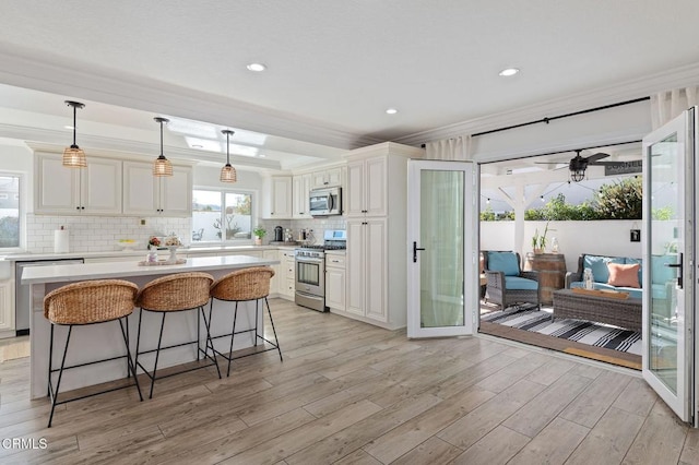 kitchen with a breakfast bar, white cabinetry, a center island, stainless steel appliances, and light hardwood / wood-style flooring