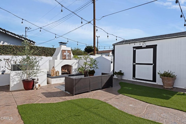 view of yard featuring an outdoor living space with a fireplace, an outbuilding, and a patio area