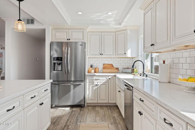 kitchen featuring appliances with stainless steel finishes, sink, ornamental molding, light stone counters, and light wood-type flooring