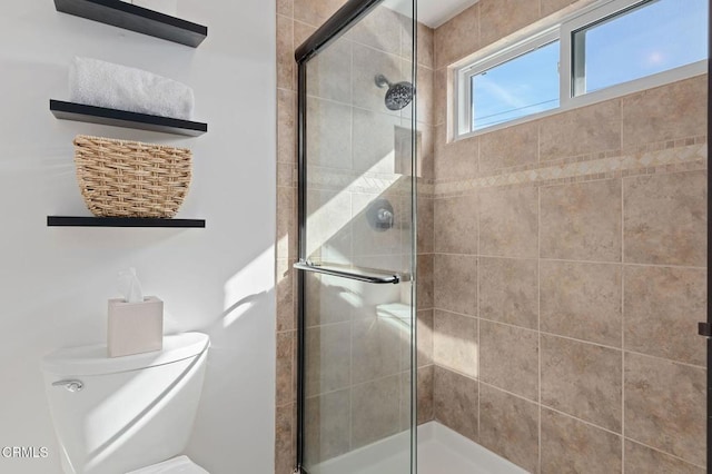 bathroom featuring a shower with shower door and toilet