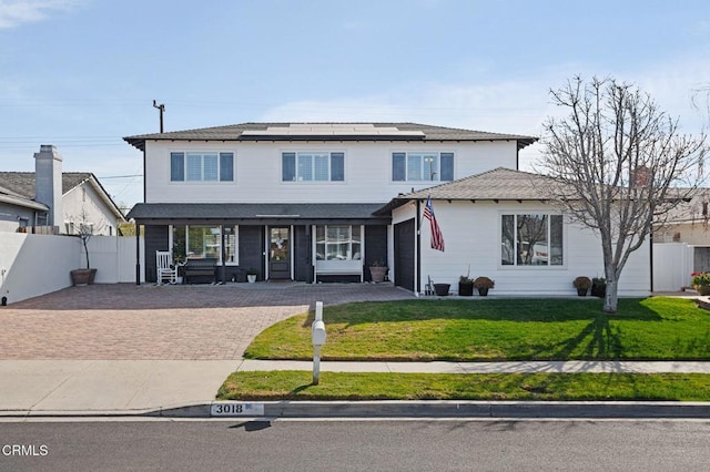 view of front property featuring covered porch, a front yard, and solar panels