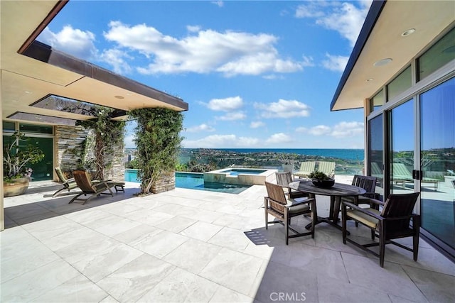 view of patio / terrace featuring a swimming pool with hot tub and a water view