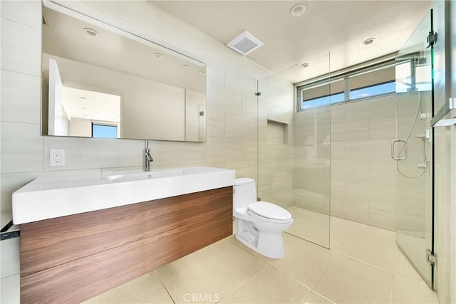 bathroom featuring tile patterned floors, toilet, tile walls, vanity, and a shower with door