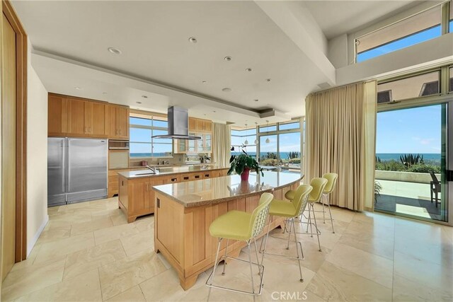 kitchen with extractor fan, a breakfast bar area, plenty of natural light, built in fridge, and a kitchen island