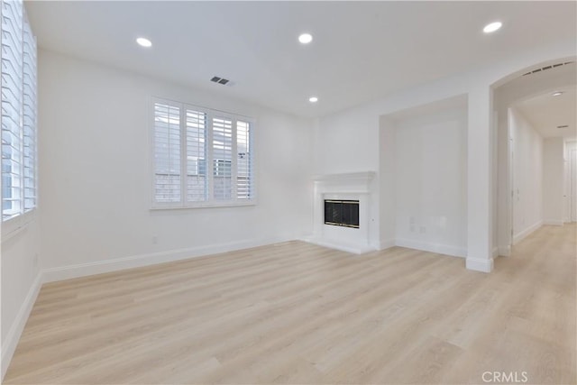 unfurnished living room featuring a wealth of natural light and light hardwood / wood-style floors