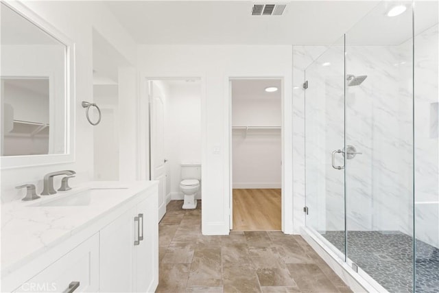 bathroom featuring walk in shower, vanity, and toilet