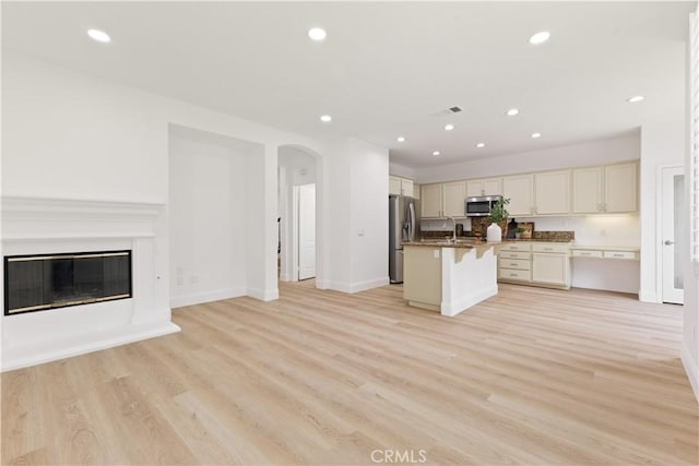 kitchen featuring stainless steel appliances, light wood-type flooring, a center island with sink, and a kitchen breakfast bar