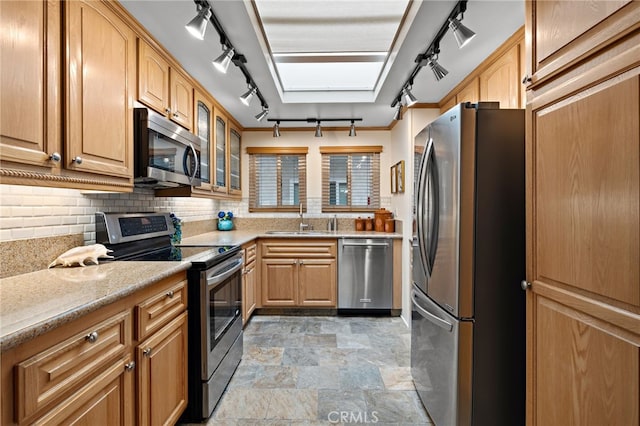 kitchen featuring stainless steel appliances, rail lighting, sink, and backsplash