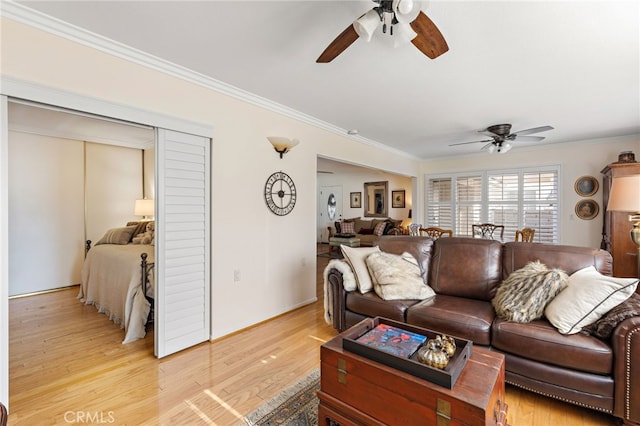 living room with crown molding, ceiling fan, and light hardwood / wood-style flooring