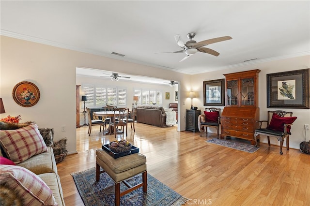 living room featuring crown molding, light hardwood / wood-style floors, and a wood stove