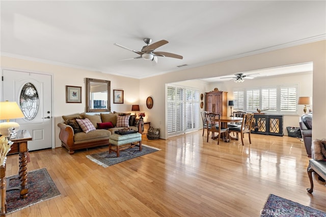 living room with crown molding, light hardwood / wood-style floors, and a wealth of natural light