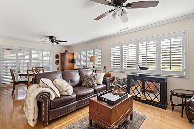 living room featuring ornamental molding, light hardwood / wood-style floors, and ceiling fan