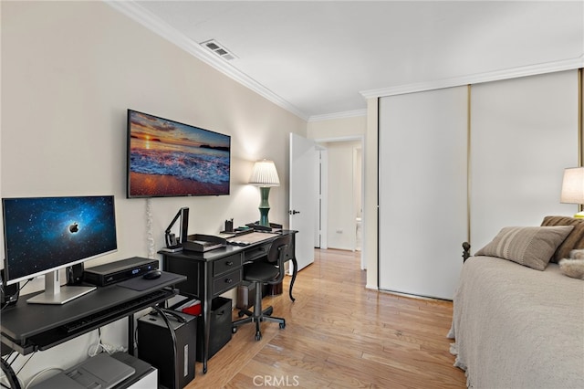 bedroom with light hardwood / wood-style flooring, ornamental molding, and a closet