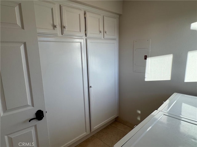 washroom featuring light tile patterned floors, electric panel, cabinet space, and washing machine and clothes dryer