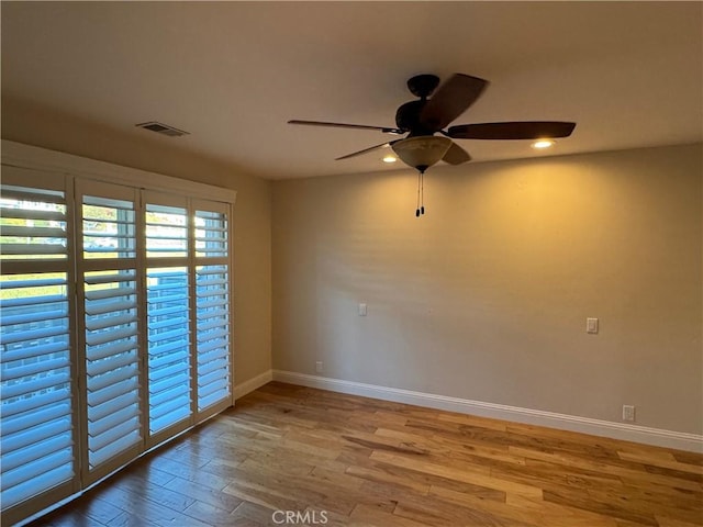 empty room with baseboards, visible vents, ceiling fan, and wood finished floors