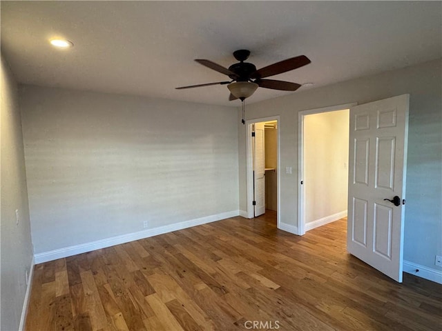 unfurnished bedroom featuring a ceiling fan, a closet, baseboards, and wood finished floors