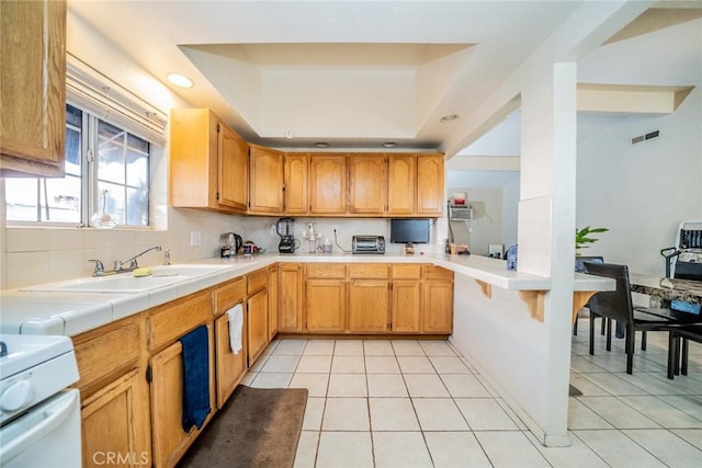 kitchen with sink, light tile patterned floors, tile counters, and decorative backsplash