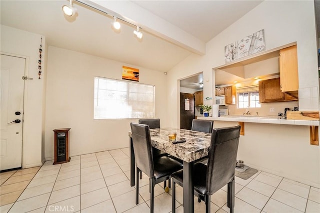 tiled dining room featuring lofted ceiling with beams