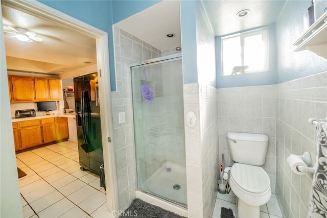 bathroom featuring tile patterned flooring, a shower with door, tile walls, and toilet