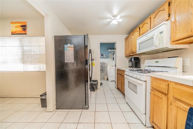 kitchen featuring tile counters, backsplash, white appliances, and light tile patterned floors