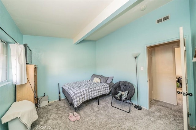 bedroom featuring beamed ceiling and light colored carpet