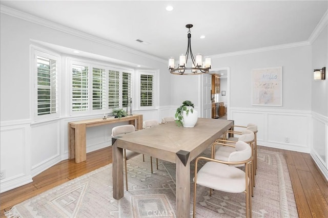 dining room with crown molding, a chandelier, and light wood-type flooring