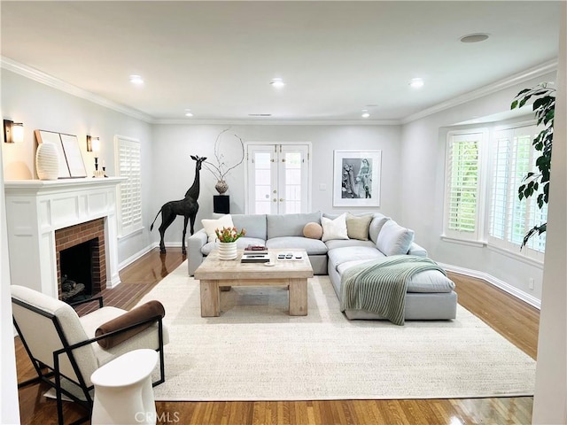 living room with a brick fireplace, crown molding, french doors, and hardwood / wood-style flooring