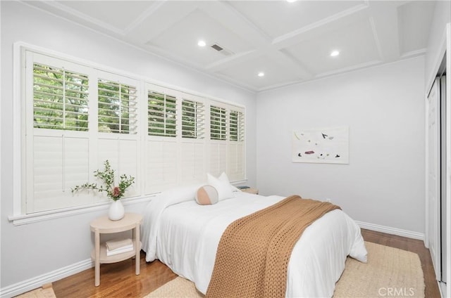 bedroom with coffered ceiling, hardwood / wood-style floors, and beam ceiling