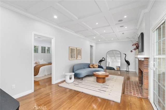 sitting room with hardwood / wood-style flooring, crown molding, beam ceiling, coffered ceiling, and a fireplace