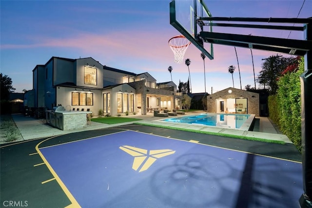 view of basketball court with an outdoor pool, basketball court, and an exterior structure