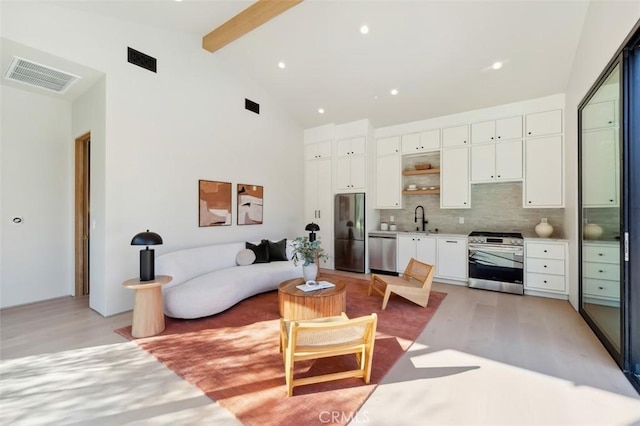 living area featuring visible vents, beamed ceiling, and light wood-style flooring