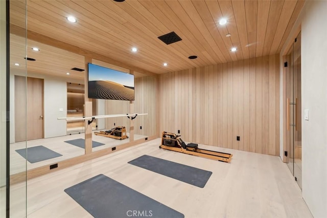 workout area featuring wood ceiling, light hardwood / wood-style flooring, and wood walls