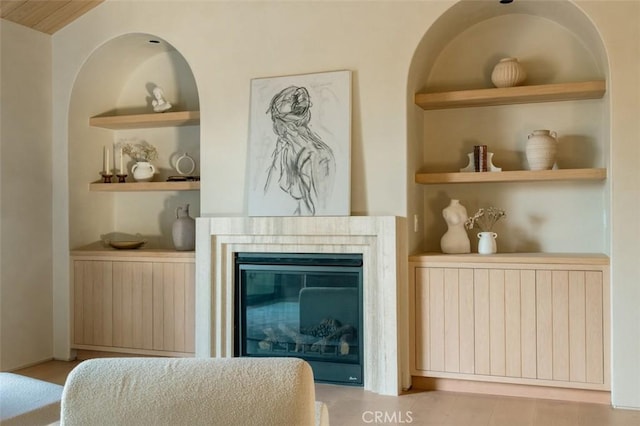 living room featuring built in shelves, a glass covered fireplace, and radiator