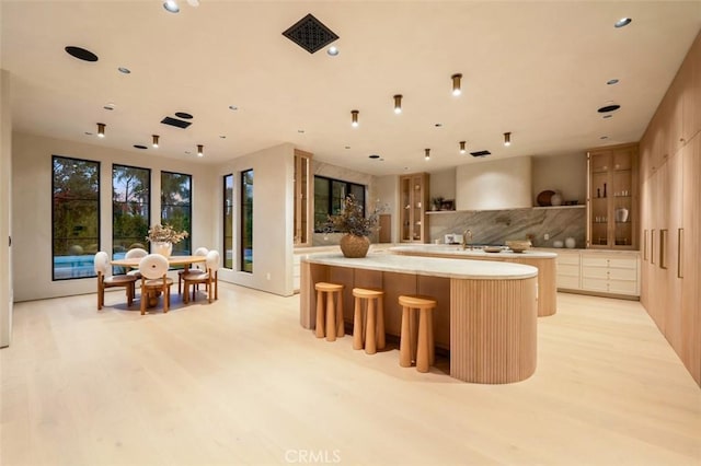 kitchen featuring tasteful backsplash, light brown cabinetry, a breakfast bar area, and light wood-type flooring