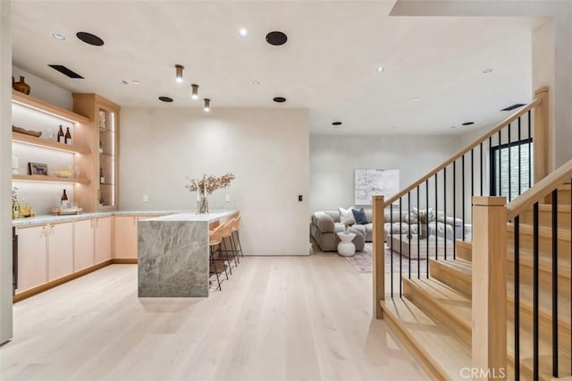 bar with light brown cabinetry and light hardwood / wood-style flooring