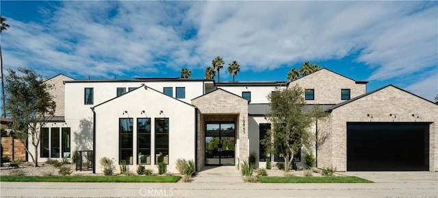 view of front facade with an attached garage, solar panels, brick siding, concrete driveway, and stucco siding