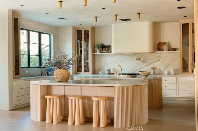 bar with light wood-type flooring, backsplash, and a sink