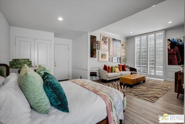 bedroom with light hardwood / wood-style flooring, ornamental molding, and a closet