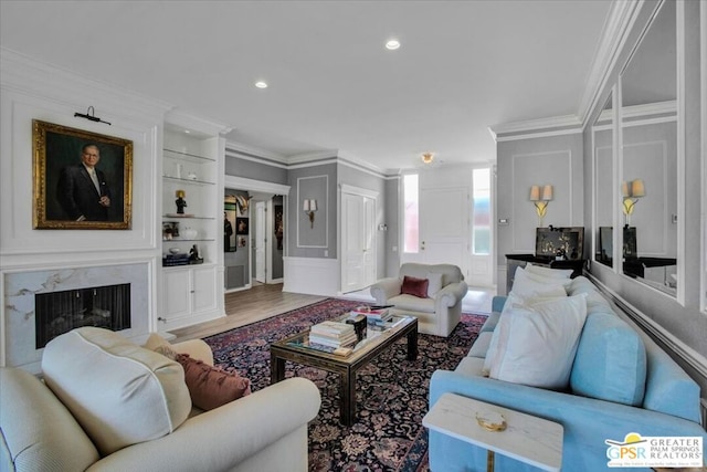 living room with crown molding, a high end fireplace, and hardwood / wood-style floors