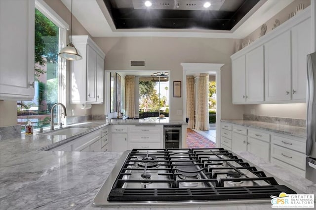 kitchen with light stone counters, white cabinets, stainless steel gas stovetop, and wine cooler