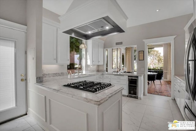 kitchen with white cabinets, beverage cooler, kitchen peninsula, stainless steel appliances, and custom range hood