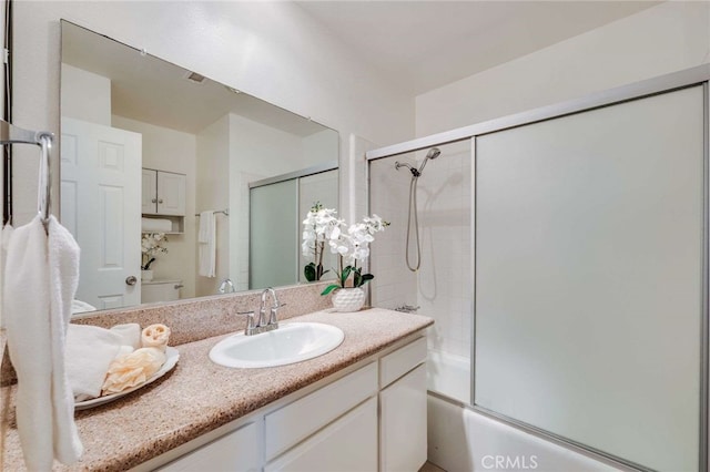 full bathroom with enclosed tub / shower combo, vanity, and toilet